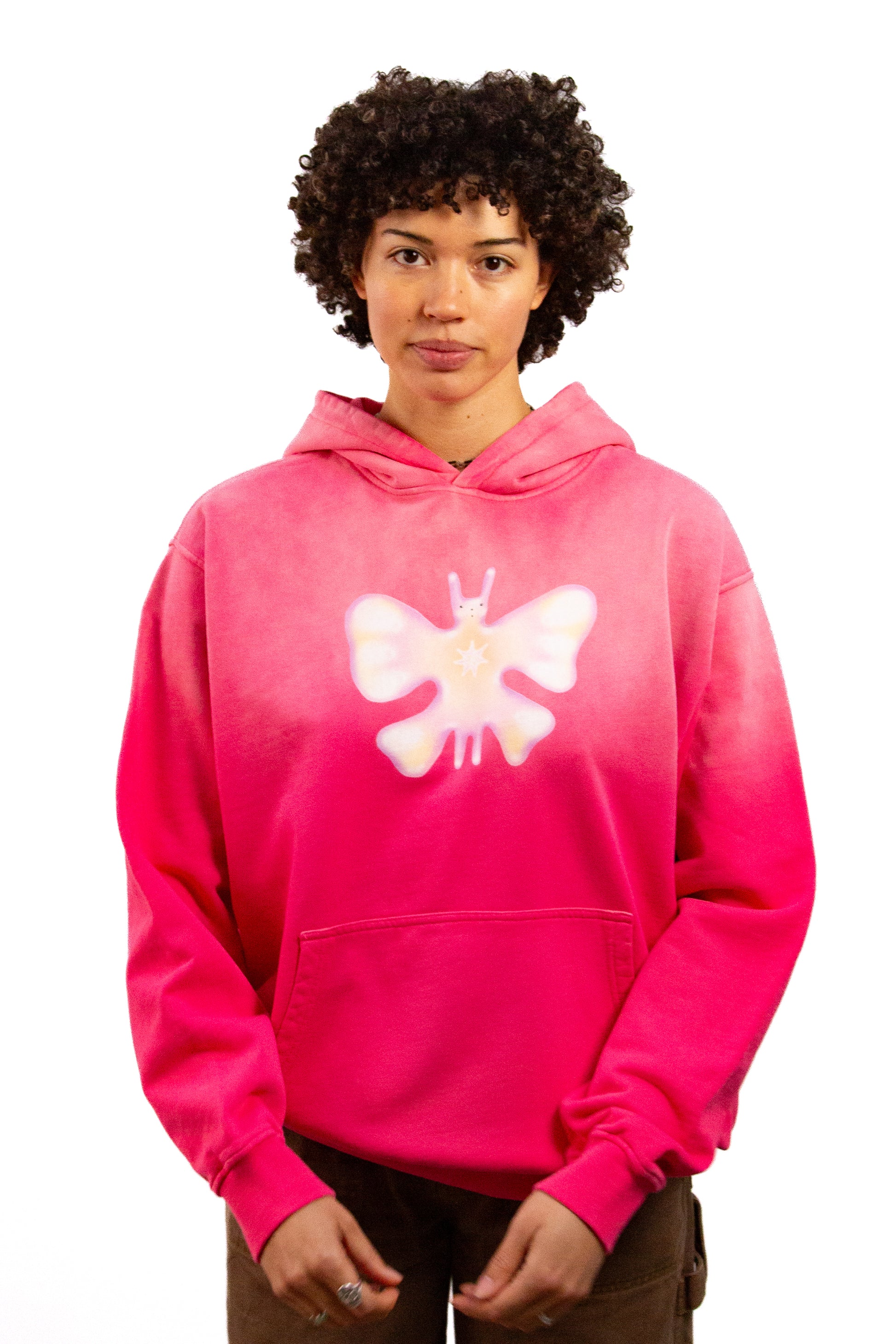 Light skinned androgynous model with natural curly hair wearing shirt in Starfruit pink